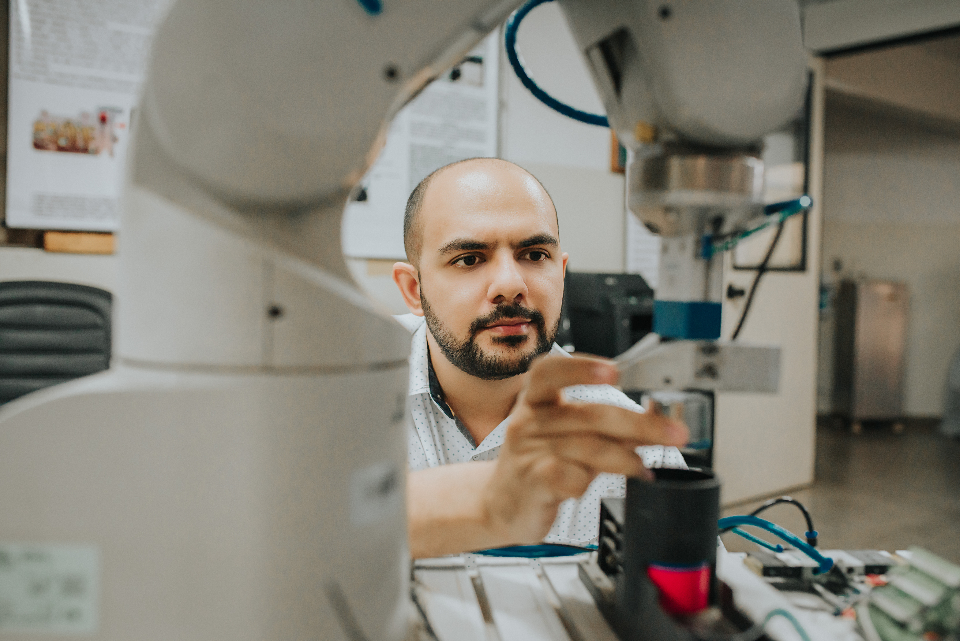 Filipe Fraga ao lado de uma bancada de automação e instrumentação industrial.